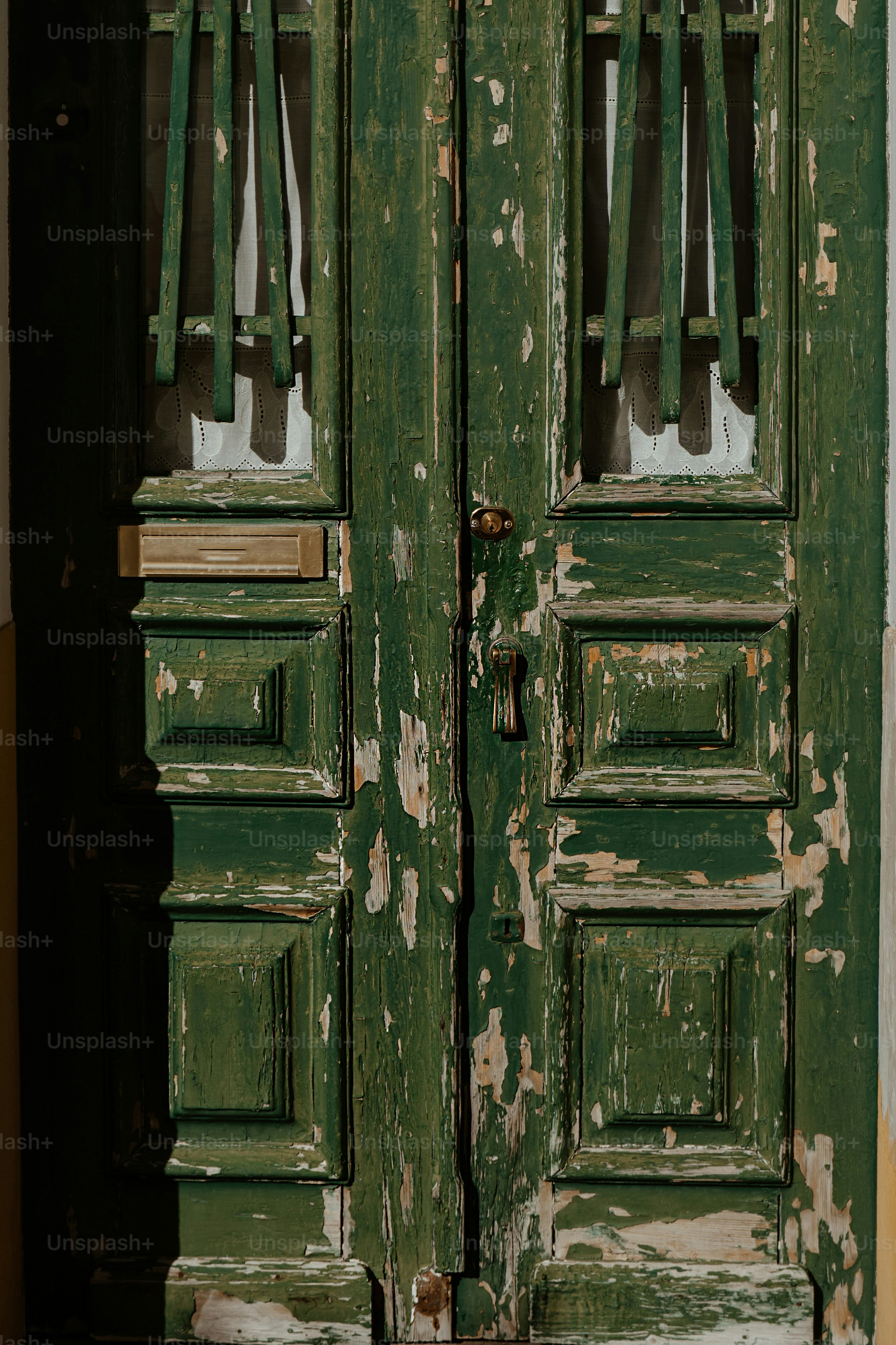 a close up of a green door with peeling paint